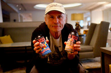 Chargez l&#39;image dans la visionneuse de la galerie, Bruce Dickinson, lead singer of Iron Maiden, holding cans of Trooper Running Free non-alcoholic beer and Trooper Swedish Lager by Nils Oscar, showcasing Iron Maiden’s iconic Eddie mascot.
